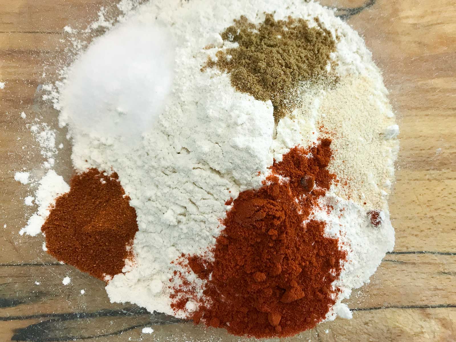 Flour and seasonings to prepare the batter for onion rings in a glass bowl.