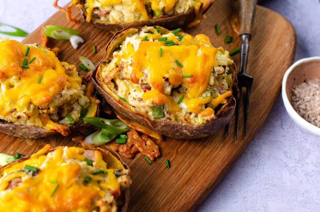 Loaded potato skins filled with cheese, onion and bacon on a wooden board.