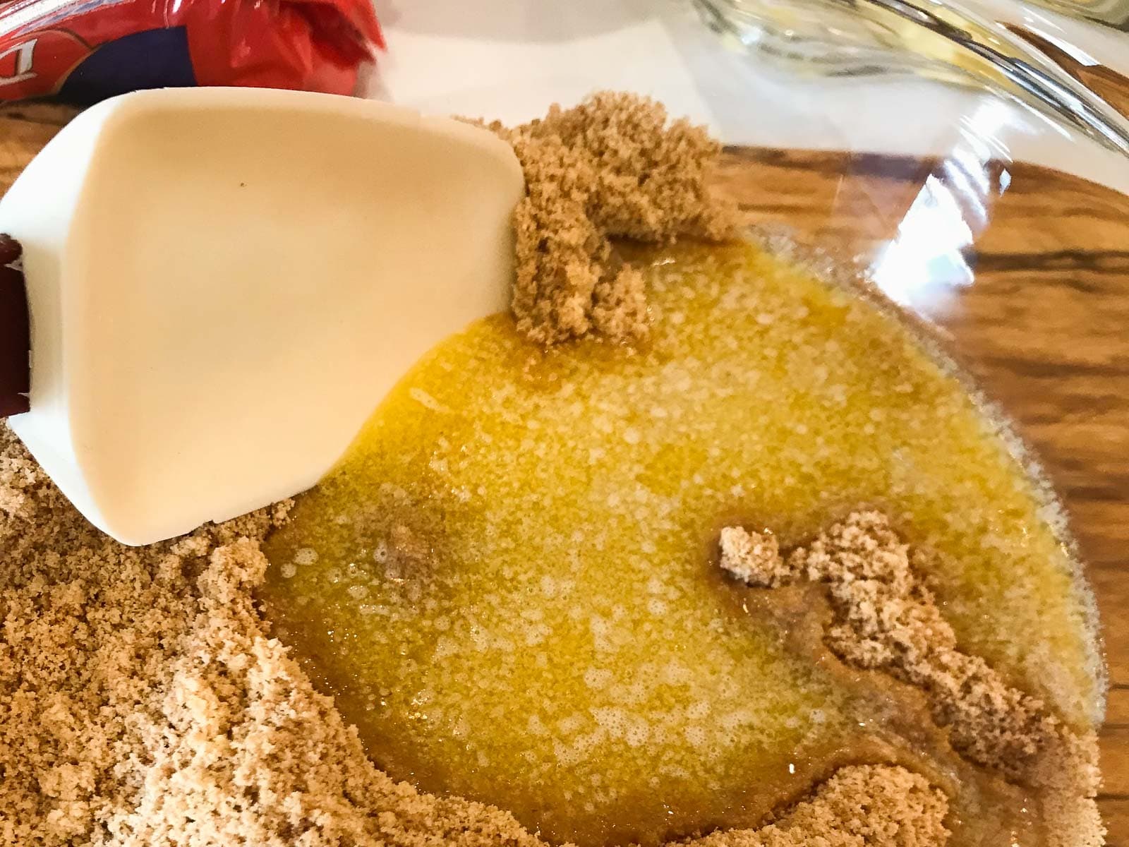Crushed digestive biscuits with added melted butter in a glass bowl.