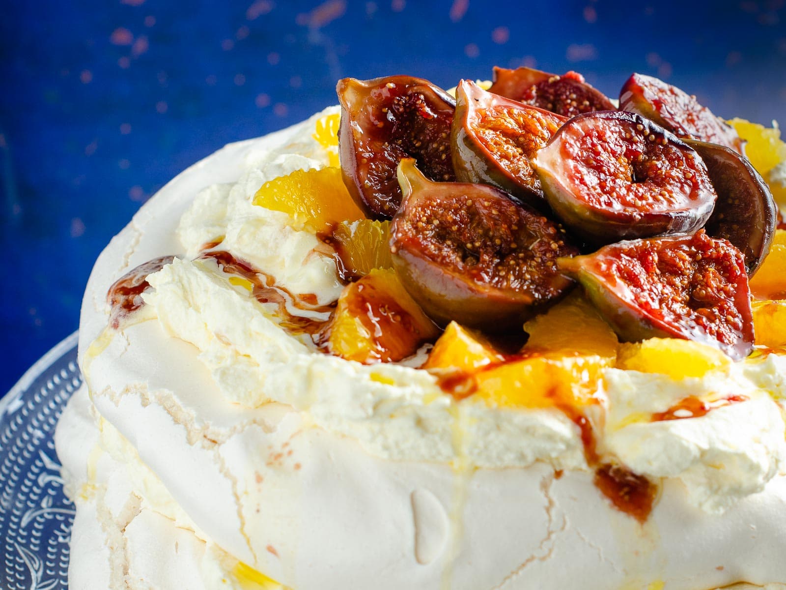 Close up of figs and orange segments on top of a sweet meringue cake.