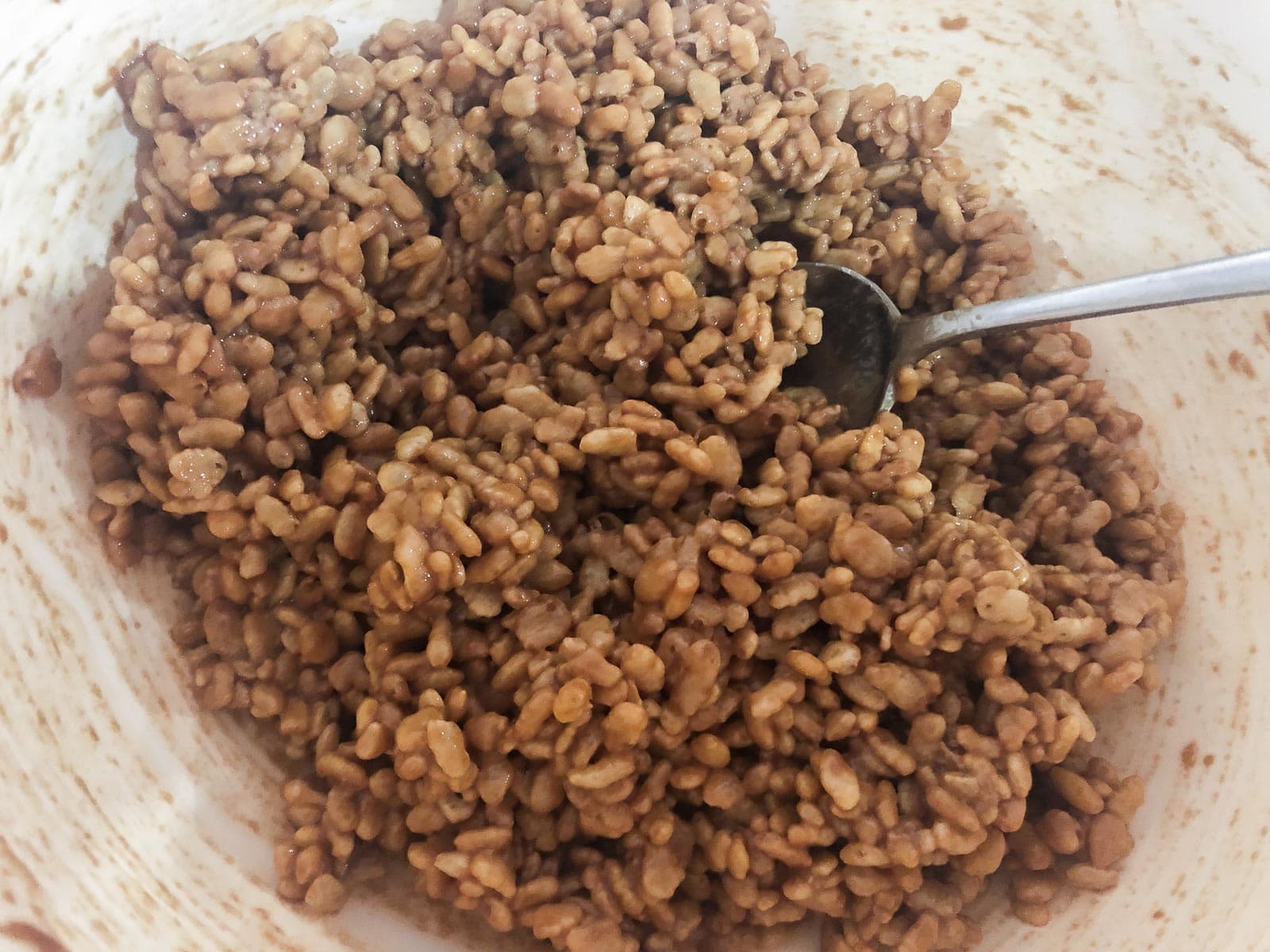 Rice krispies mixed with melted chocolate mars bars and butter in a bowl.