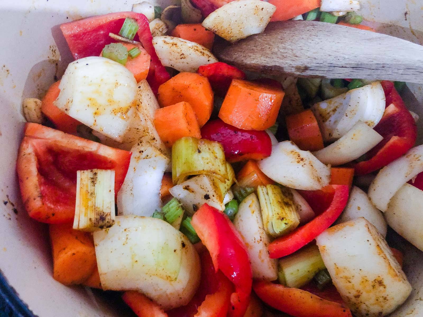 Chopped red peppers, onions, carrots and leeks mixed with paprika and cooking in a casserole pan.