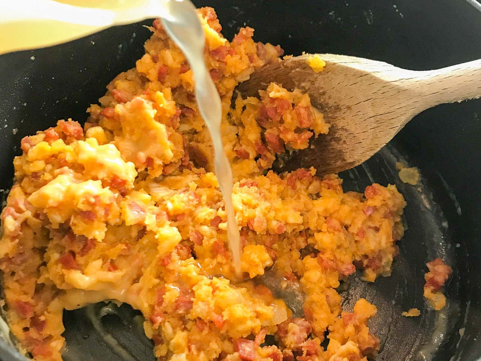 Adding stock to a croquette mixture.