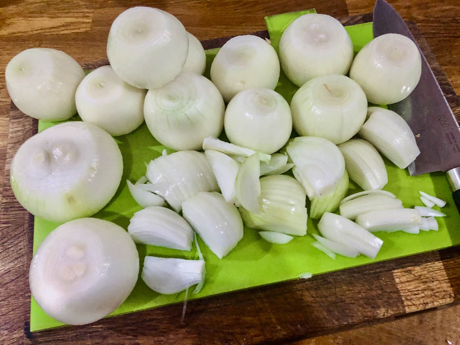A full chopping board of peeled onions to be turned into soup