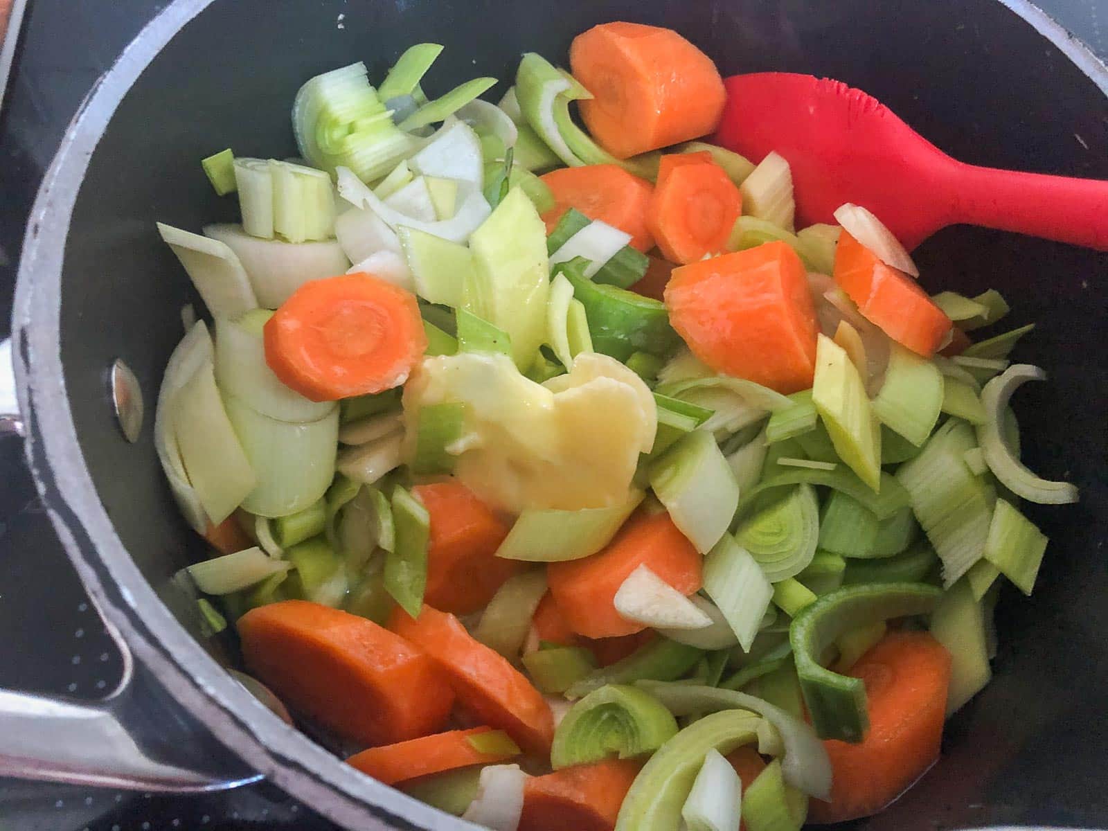 Leeks and carrots sauteeing with butter in a fry pan.