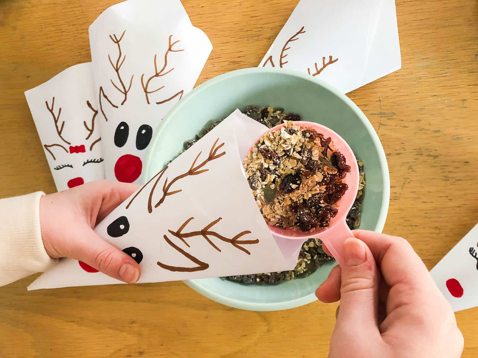 Small hands showing how to fill homemade pouches of reindeer food for Christmas Eve.