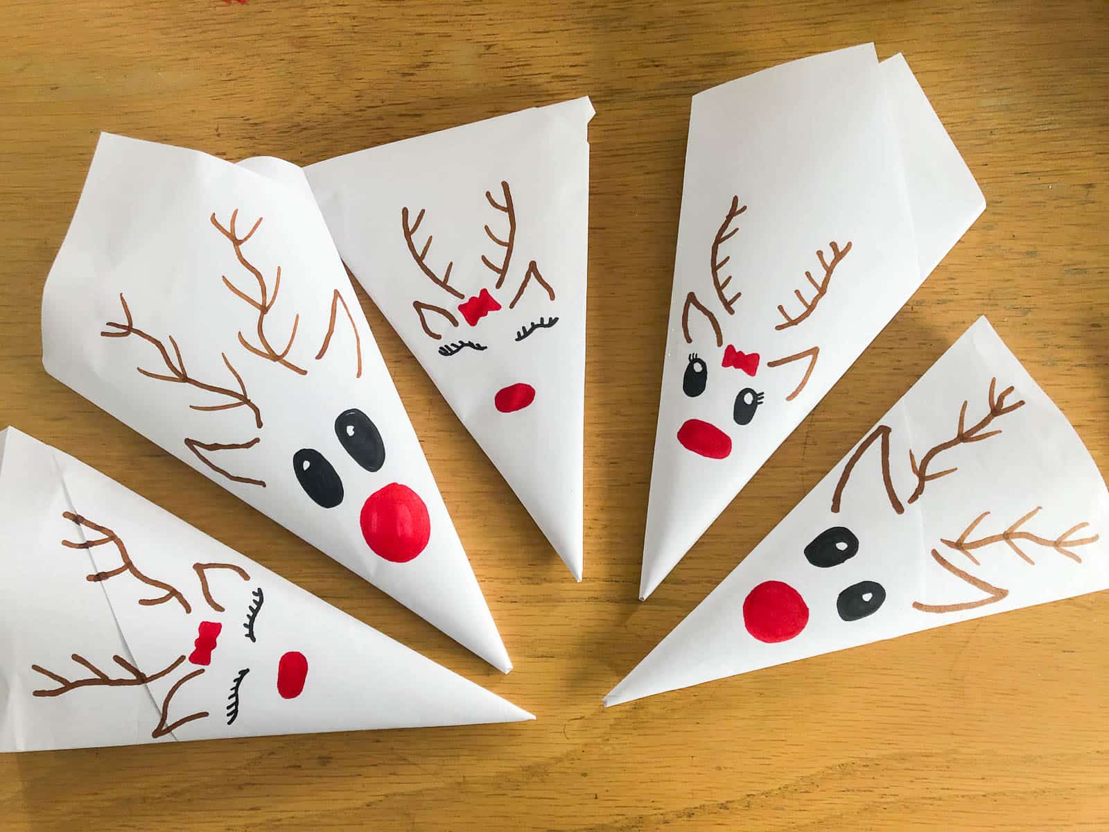 5 homemade pouches filled with reindeer food with hand drawn faces of reindeer ready for Christmas eve.