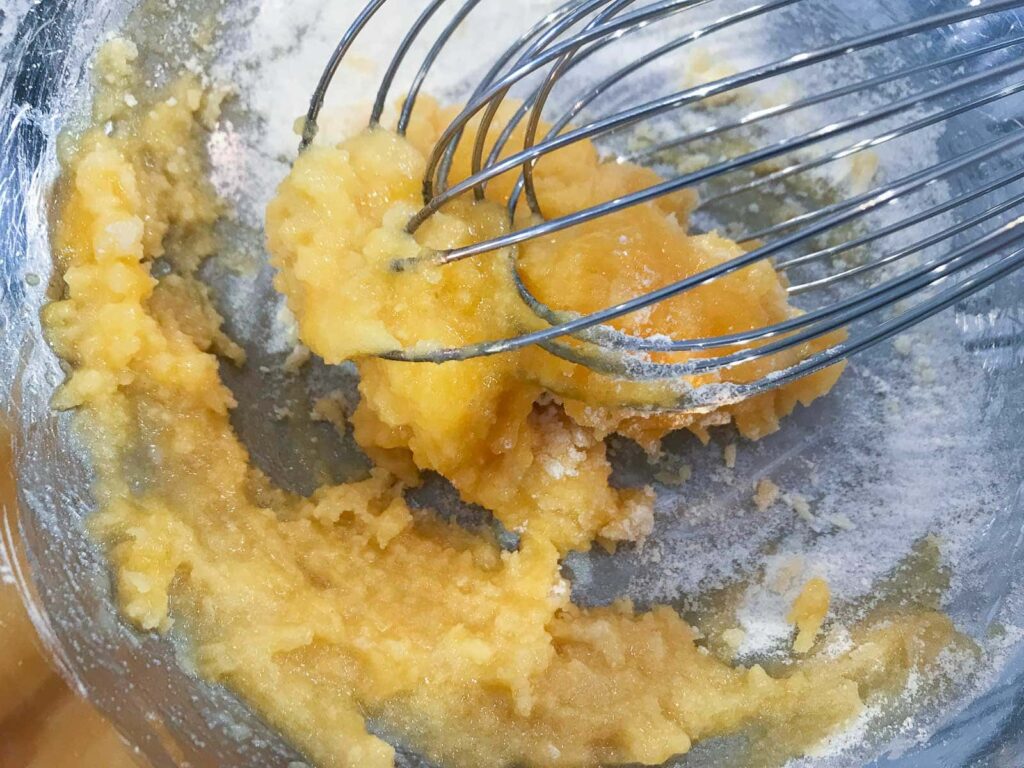 Eggs yolks and sugar being whisked until pale and fluffy.