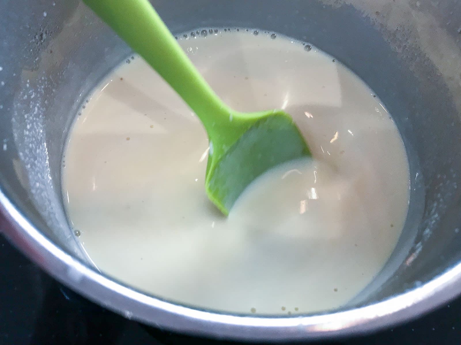 A homemade custard in a metal bowl before being thickened over heat.