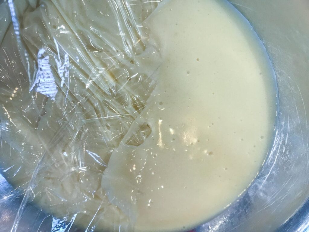 Adding cling film to the top of custard to stop a skin forming on top.