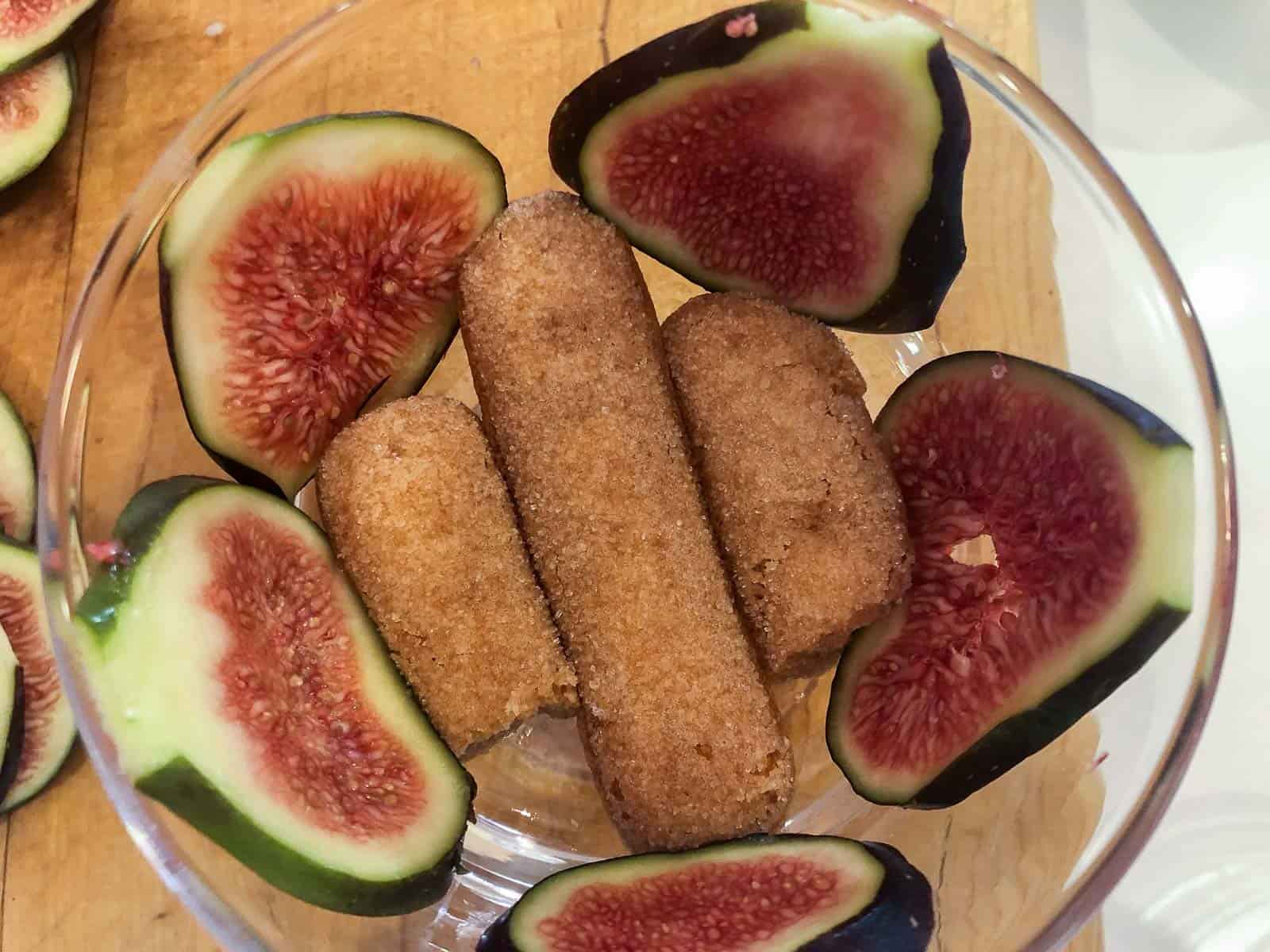 Sliced figs around the outside of a glass bowl and sherry soaked lady fingers in the bottom.