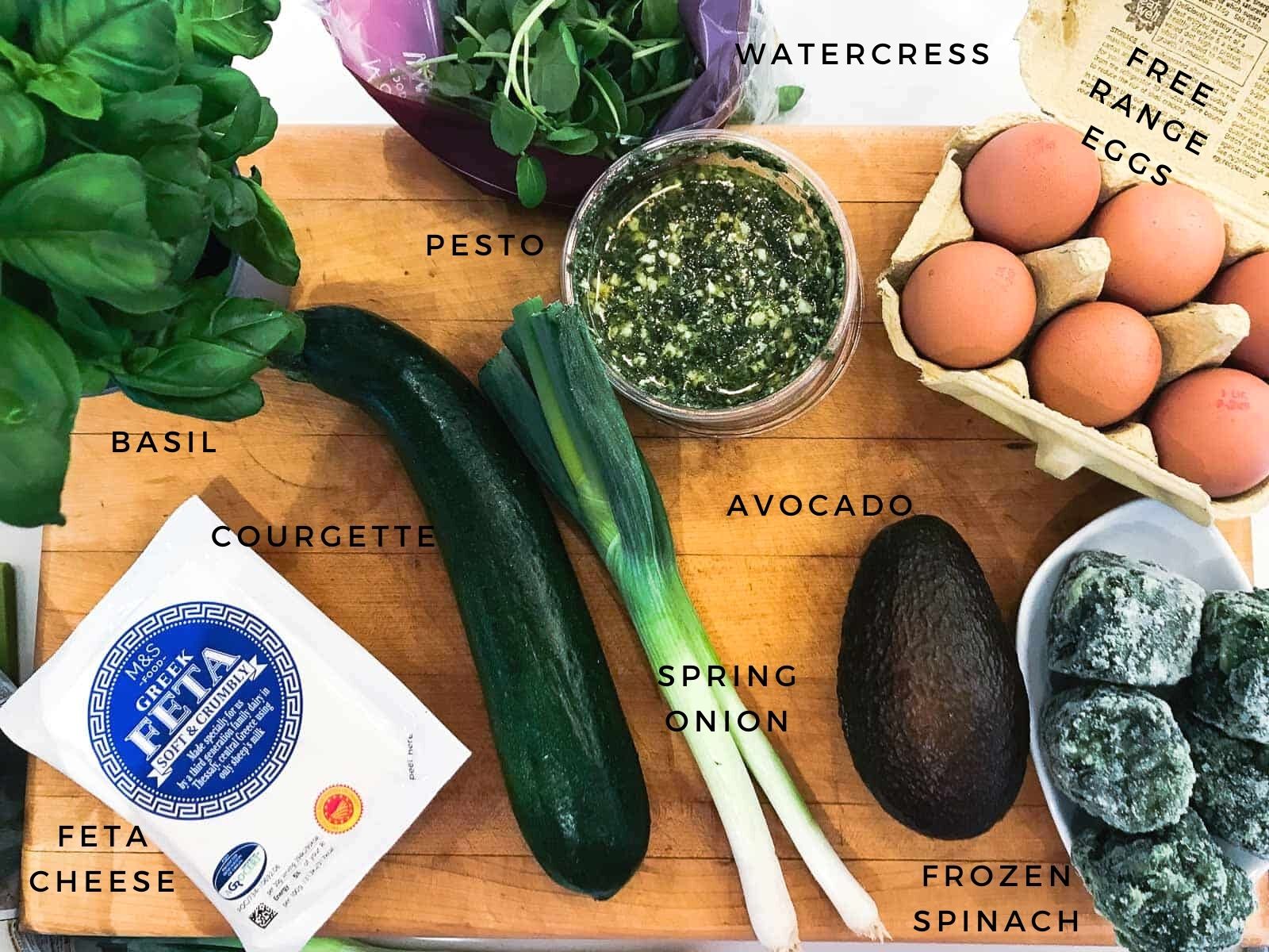 Ingredients to make a spinach omelette, icluding courgette, pesto, feta cheese, spring onions and avocado.