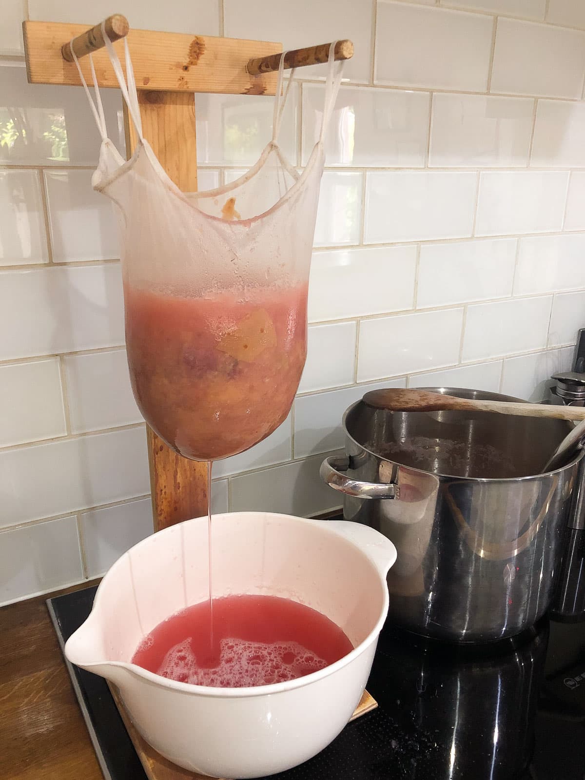 Showing the process of draining juice from cooked apples to make a jelly using a homemade jelly stand.