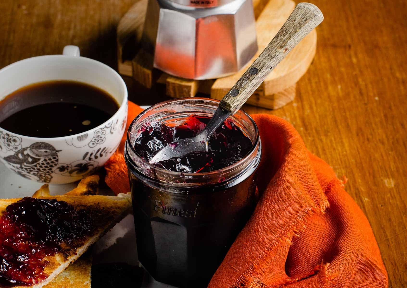 A breakfast tray of fresh homemade jelly, slices of toast and a freshly brewed coffee.
