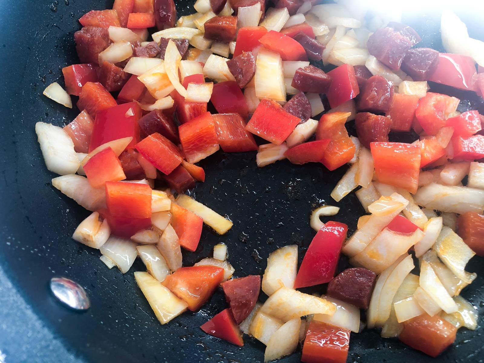 onions, red peppers and chorizo frying with the oils from the chorizo starting to leak out to colour the vegetables a lovely red.