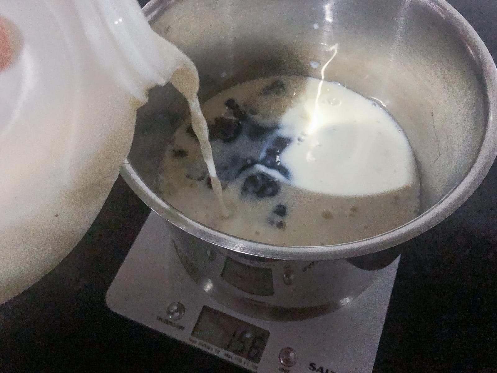 pouring milk into a pan to weigh it out.