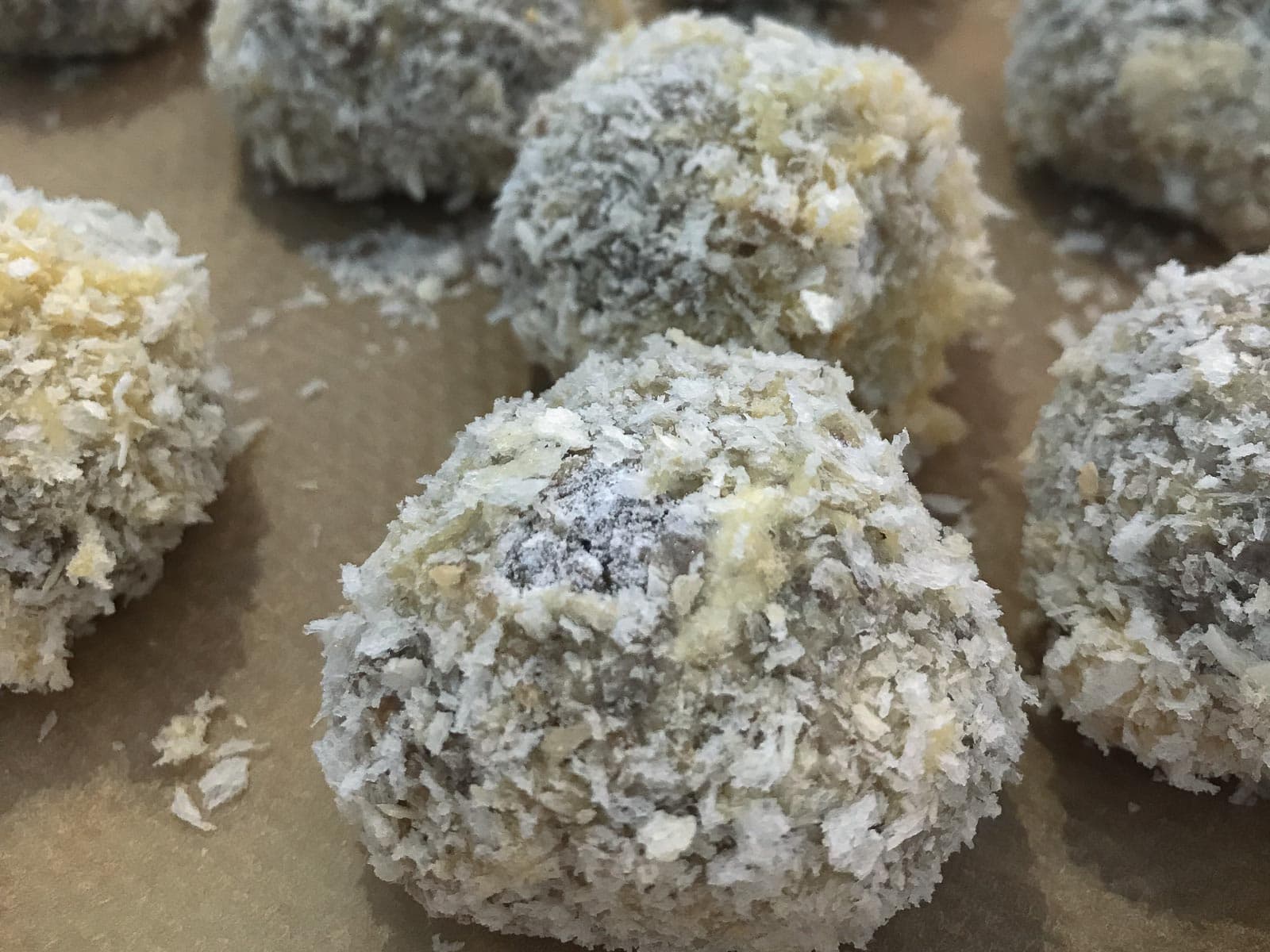 Pork balls coated in panko breadcrumbs sitting on a baking parchment lined tray.