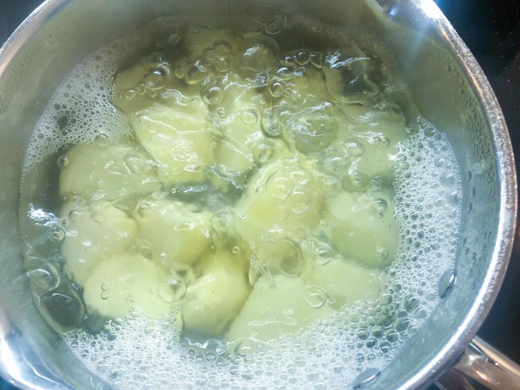 Potatoes boiling in a pan of water.