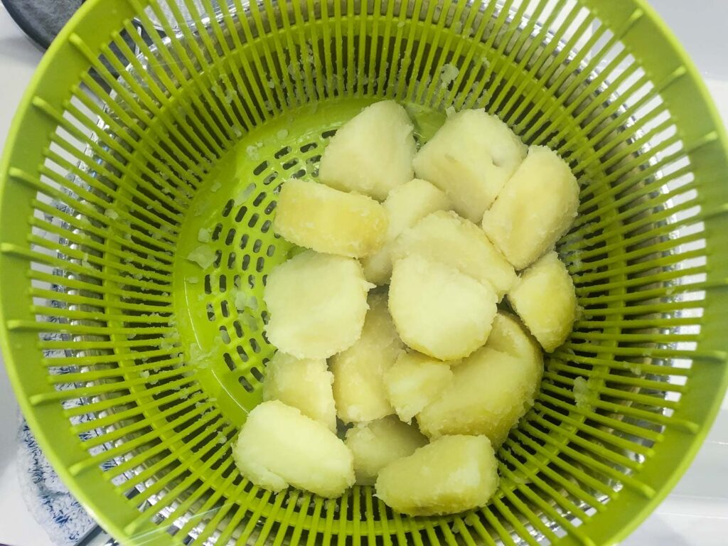 Drained boiled potatoes resting in a colander.