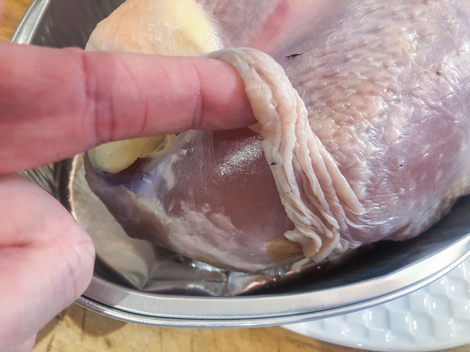 an image showing how to lift the skin of a turkey breast to allow space to stuff butter or herbs under it.