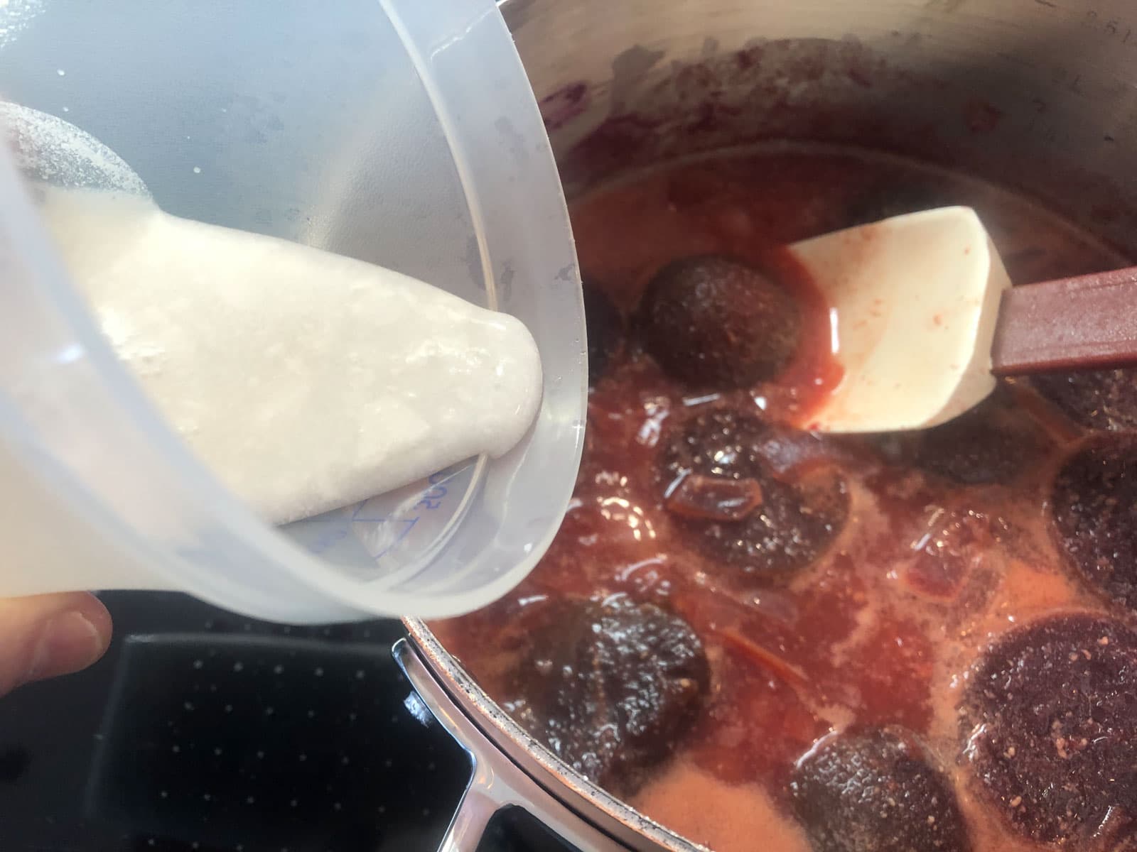 Adding coconut milk to a pan of beetroot soup