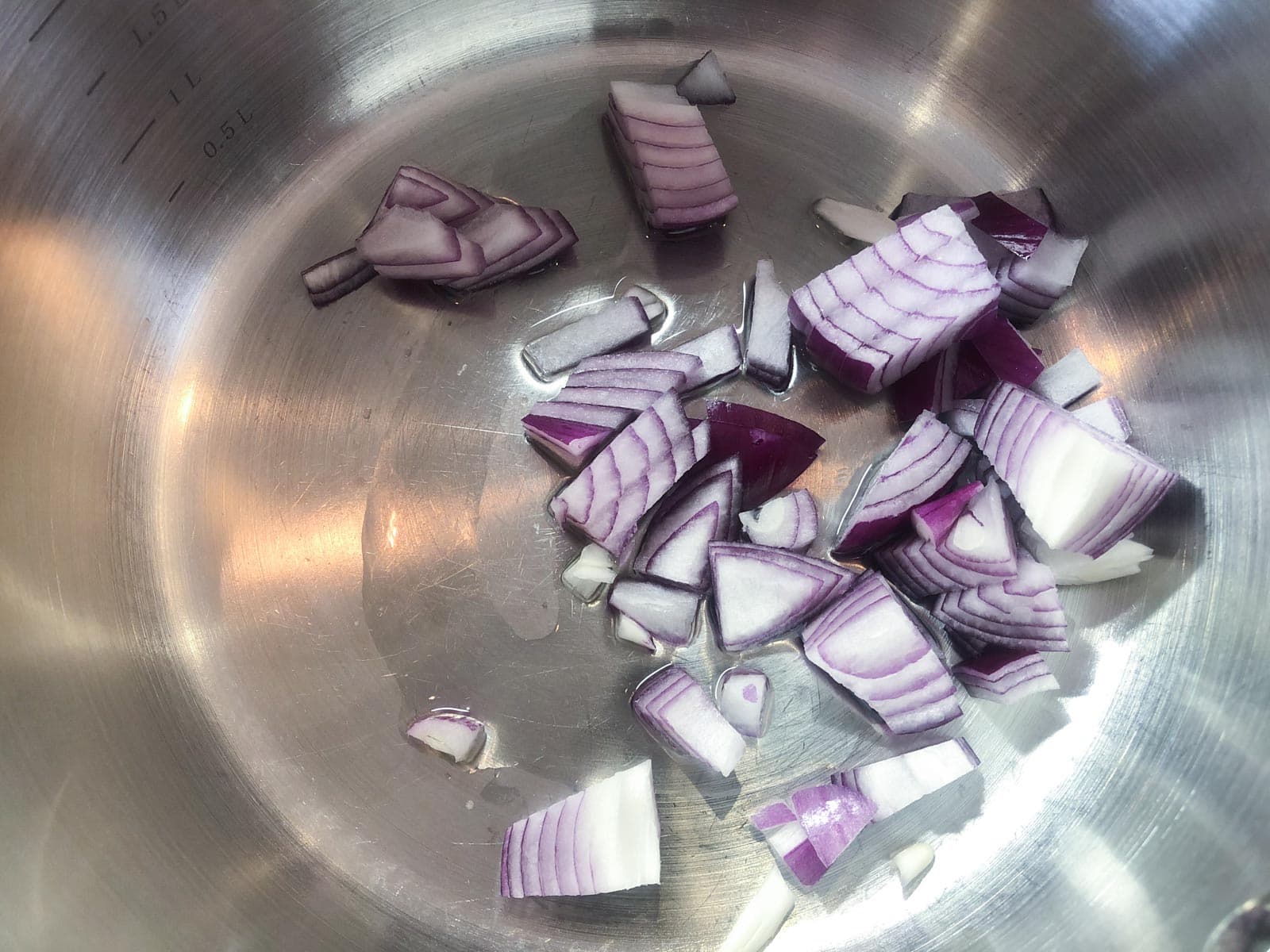 Red onions frying in oil in a large pan.