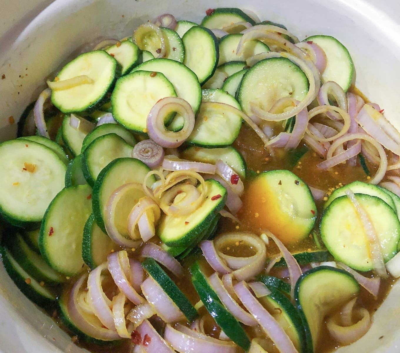 sliced courgettes and shallots in a mustard based vinegar to make a pickle.