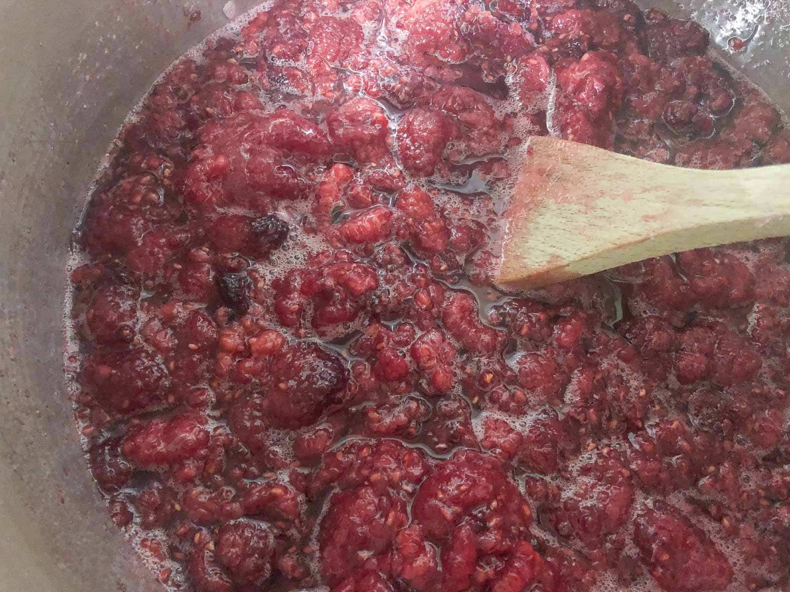 Raspberry jam simmering in a hot pan.