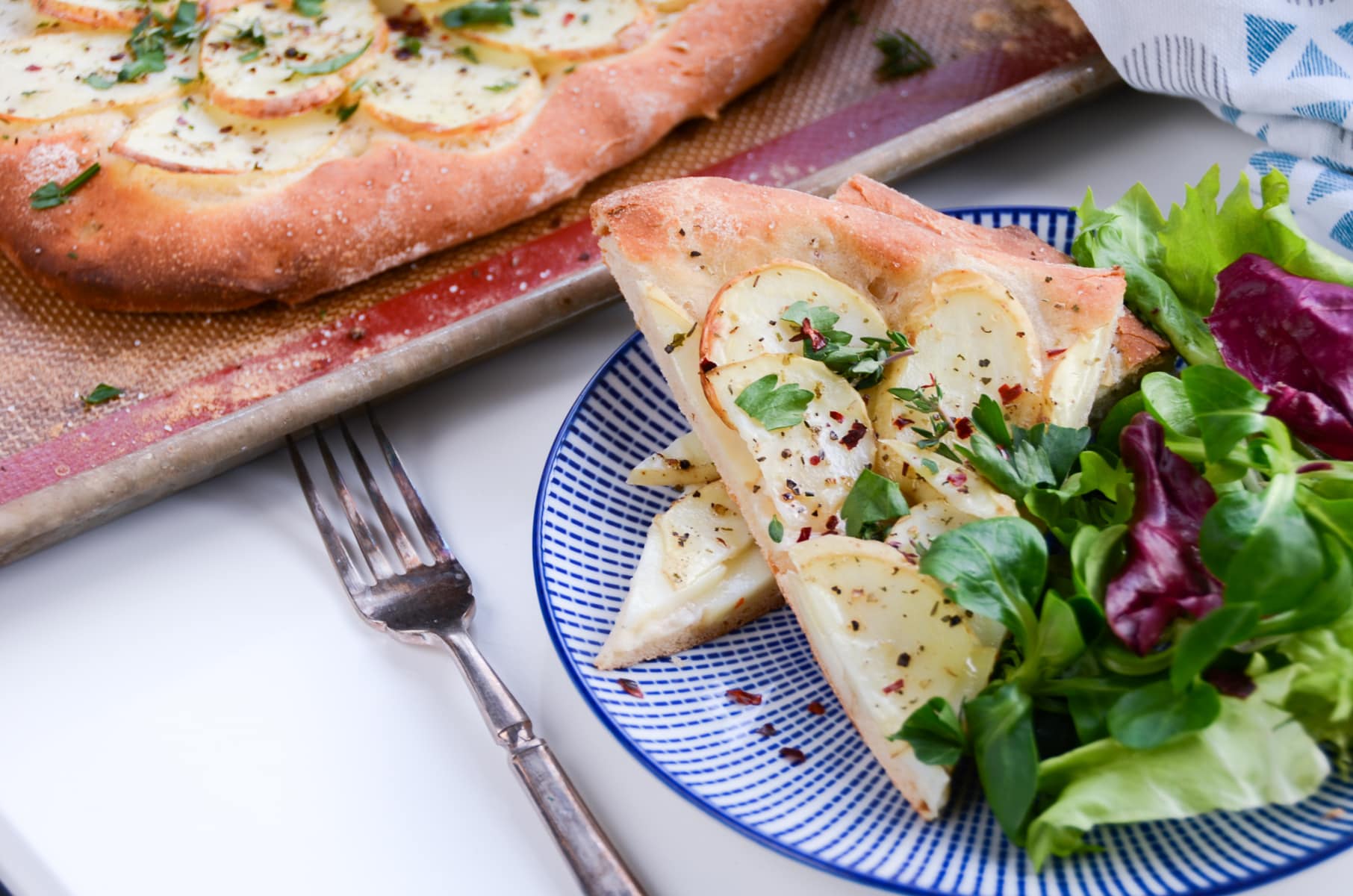 A potato galette cut into slices and served with a side green salad.