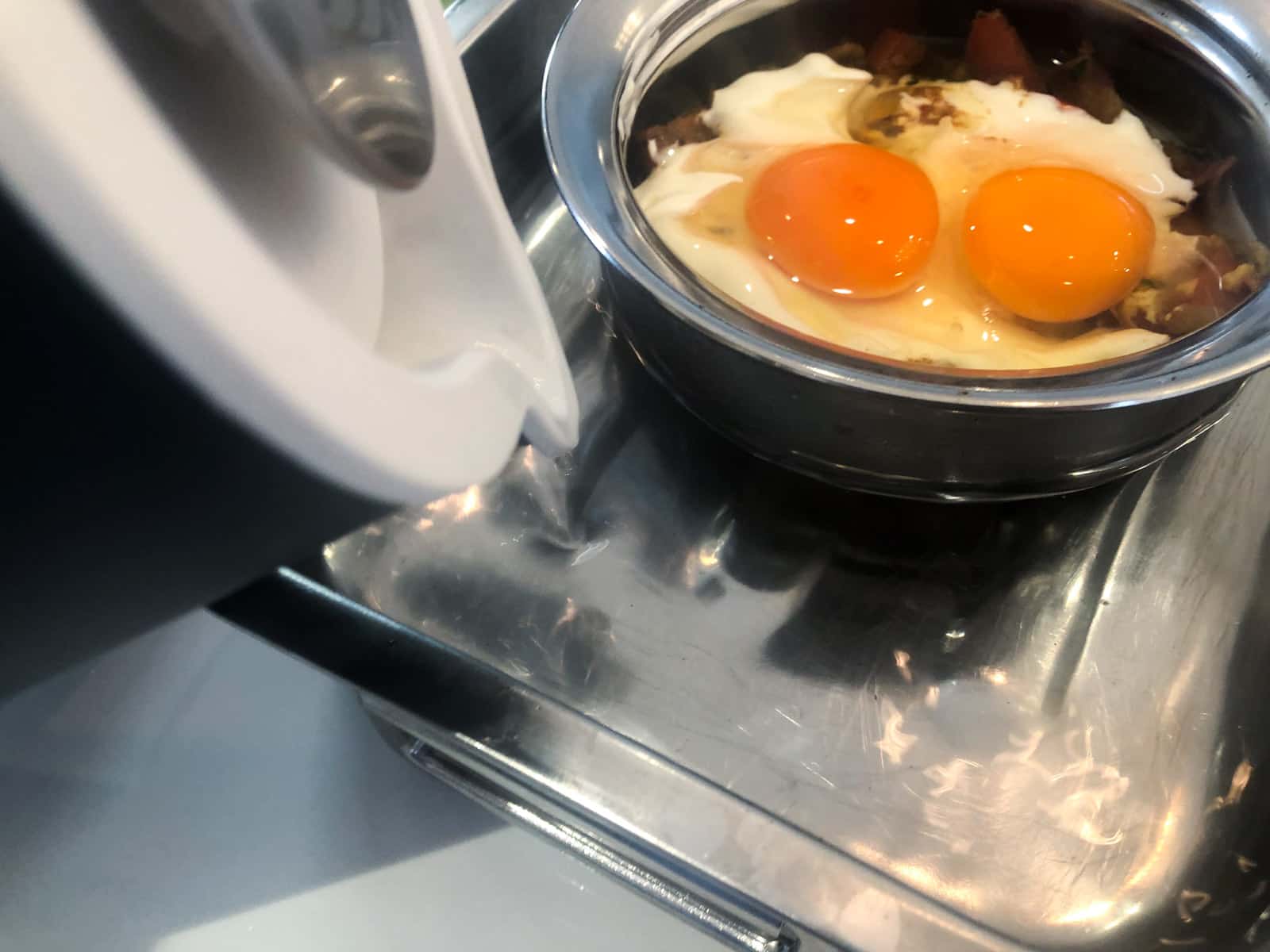 Adding boiling water to a baking tray to surround a baked egg dish to allow it to cook gently in the oven by forming a banmarie.
