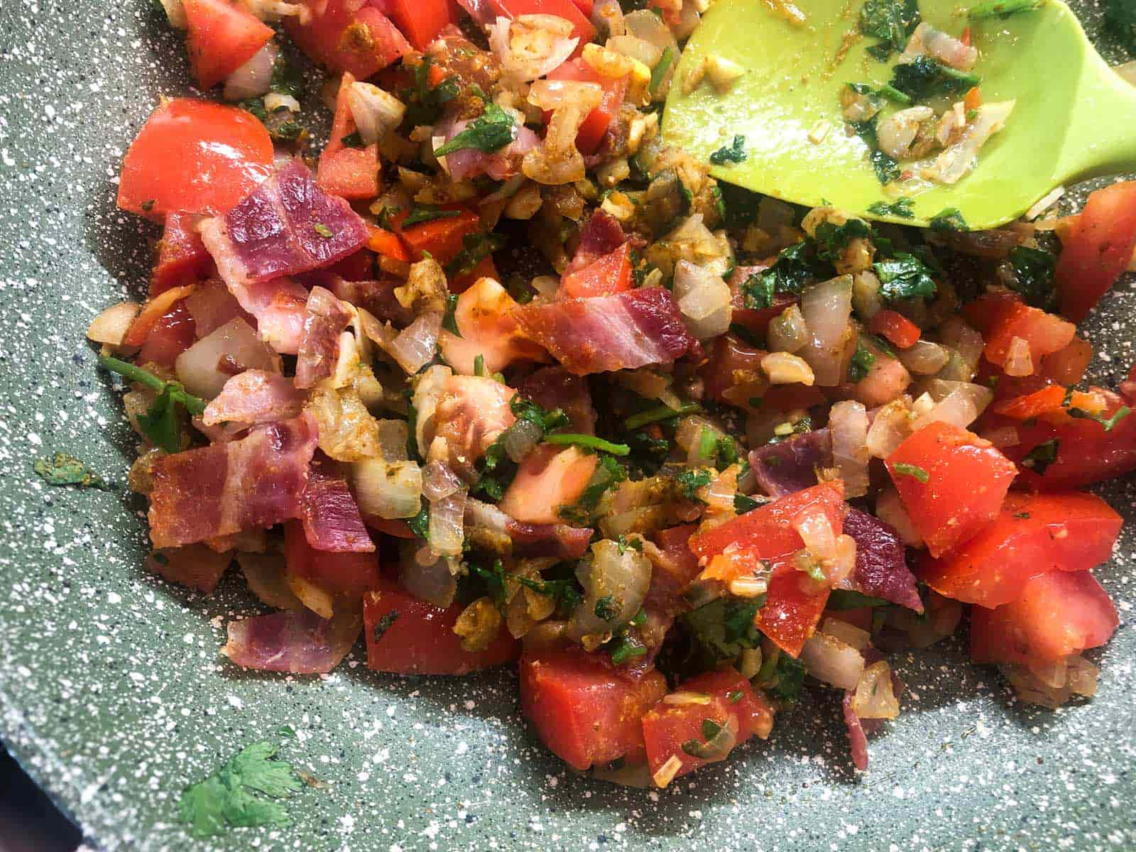 A curried base of vegetables with added cooked bacon pieces.