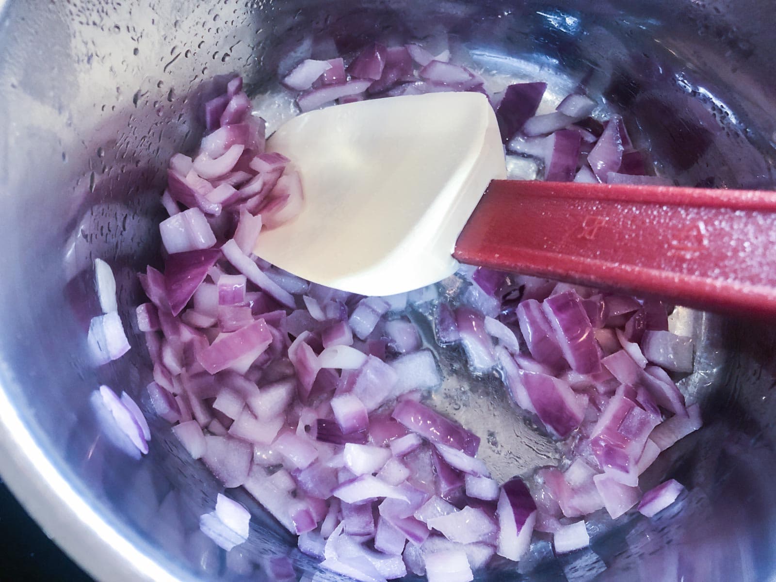 Diced red onions sauteeing in a fry pan.