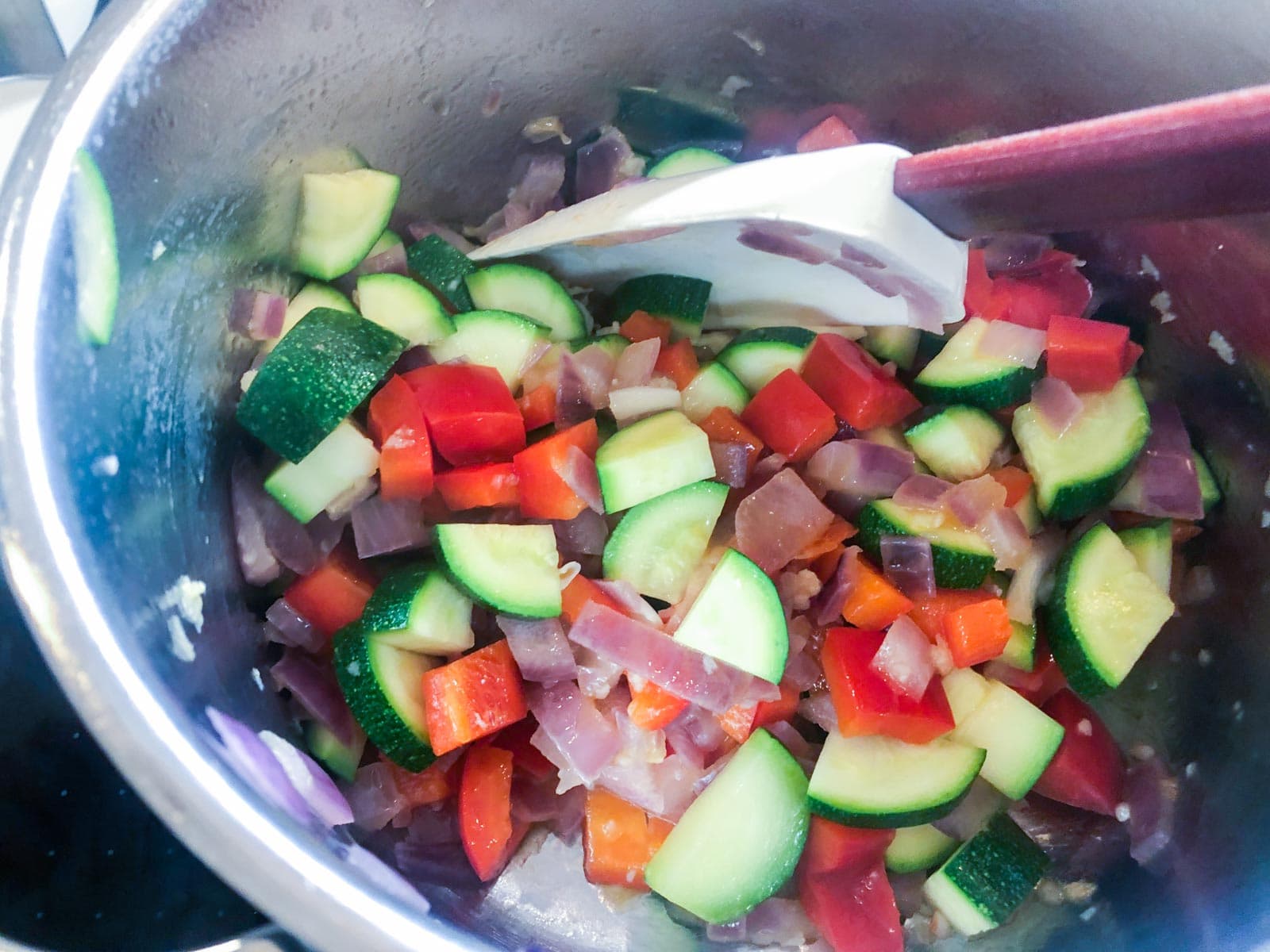 Diced red pepper, courgettes and garlic added to sauteed red onions.