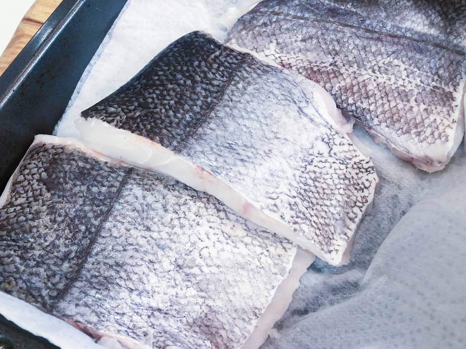 3 fillets of hake fish skin side up on a tray.