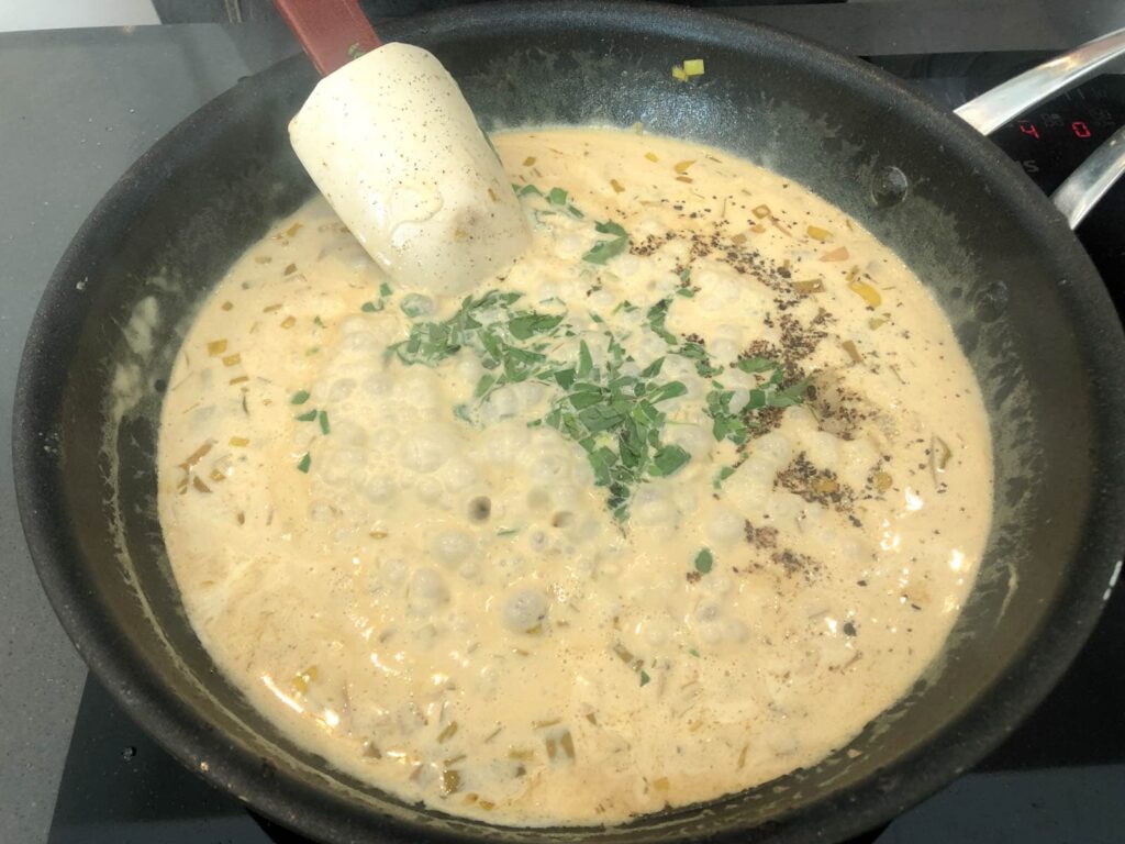 A bubbling creamy white wine and tarragon sauce in its final reduction and thickening stages.
