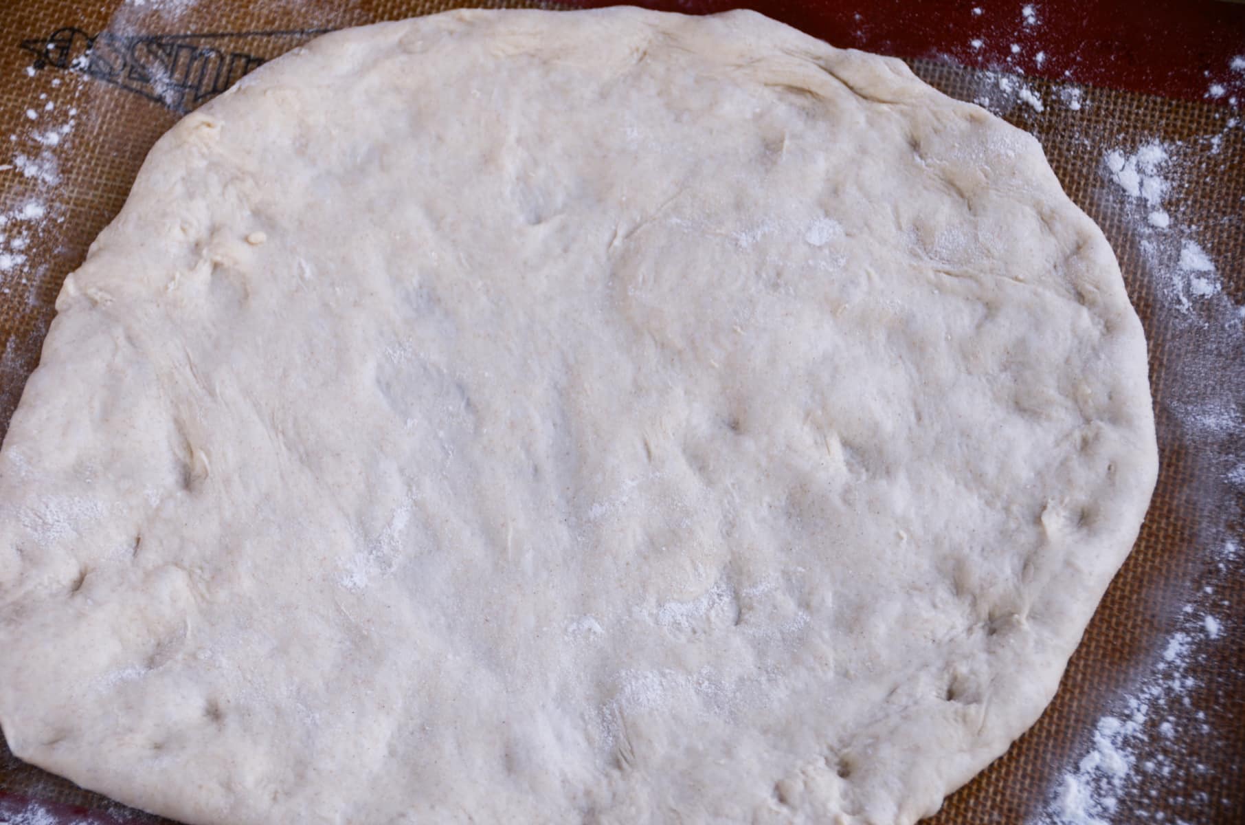 A dough rolled out and ready to top with potatoes.