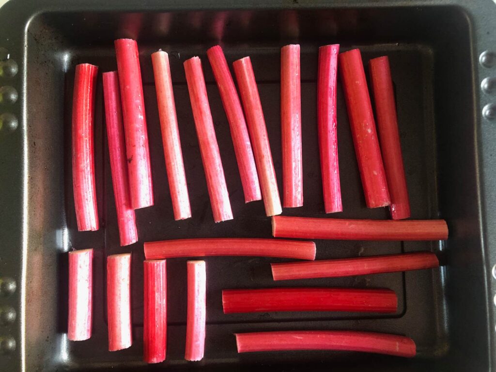 Strips of rhubarb in a baking tray to be partially roasted.
