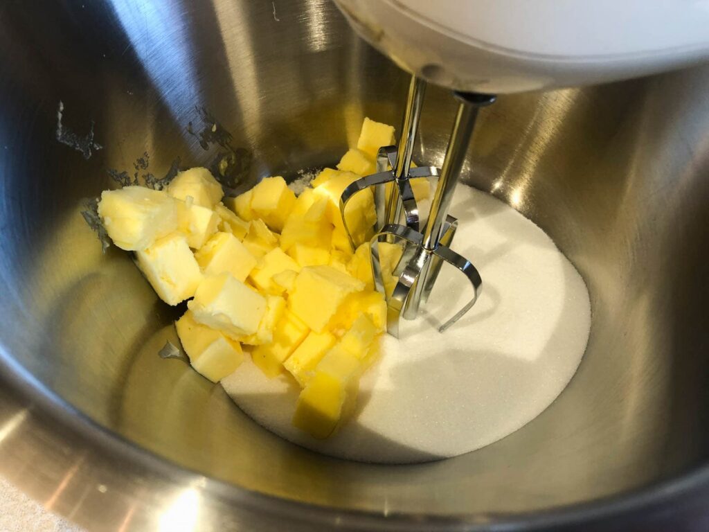 A large bowl of butter and sugar with a hand mixer about to cream together.