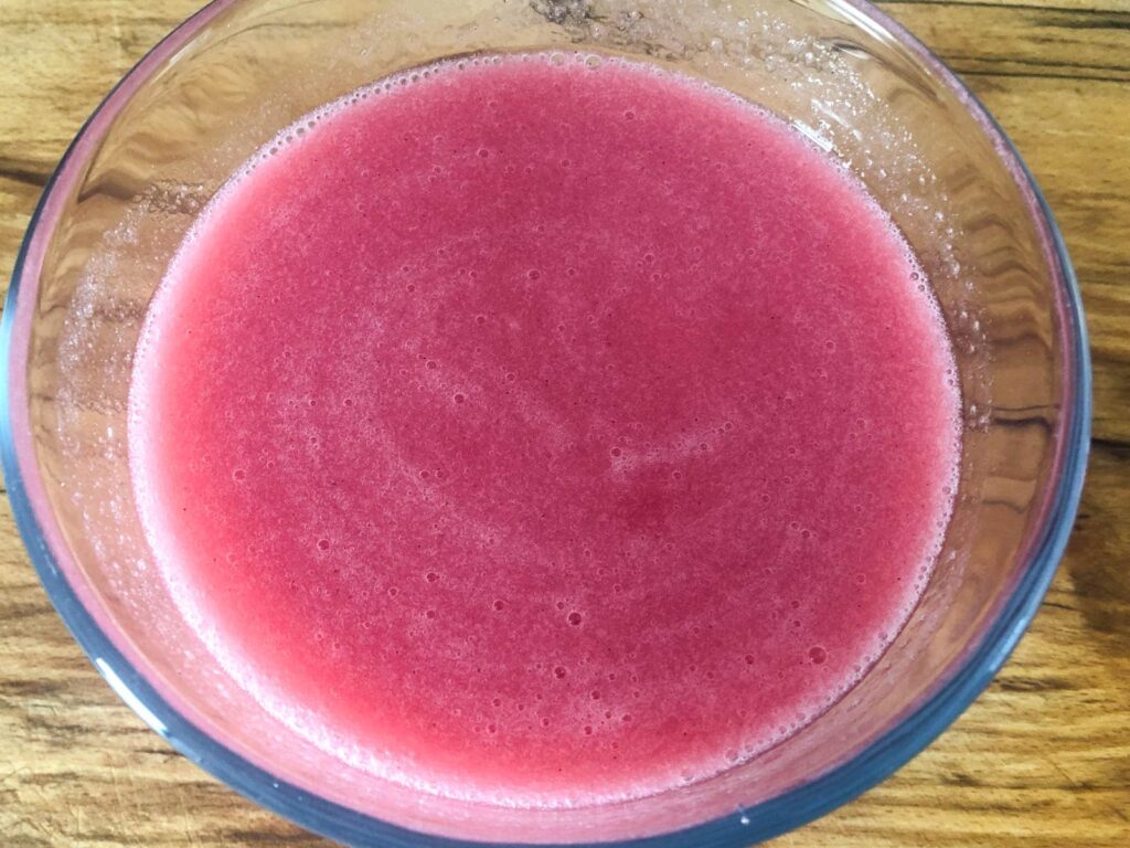 rhubarb and vanilla juice in a glass bowl on a wooden board.