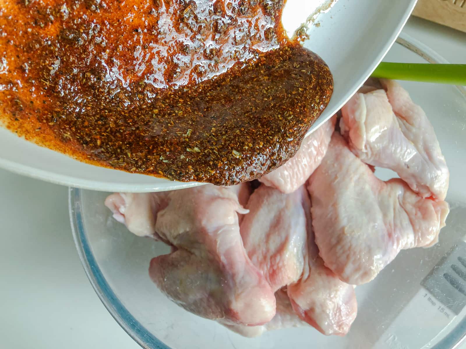 Adding a spice paste to fresh chicken wings.