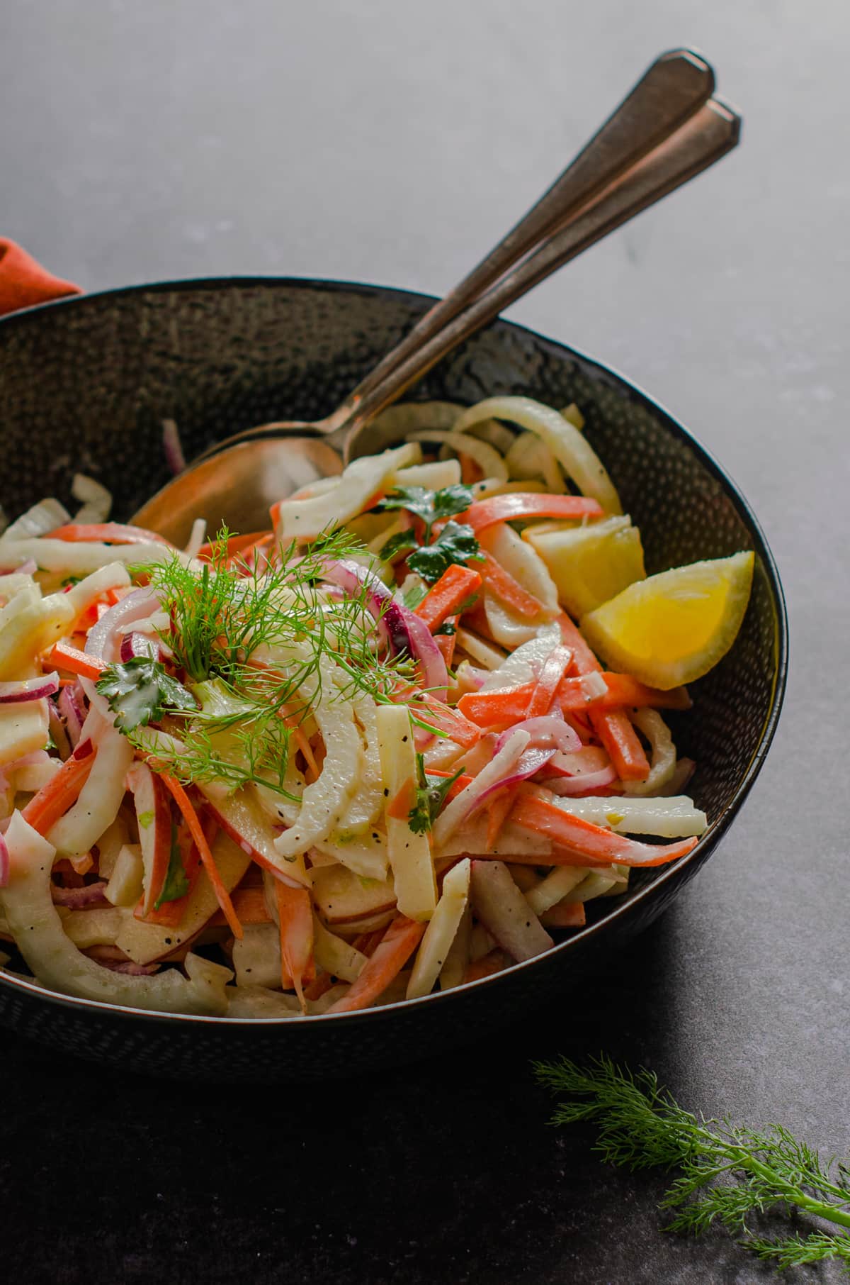 A bowl of coleslaw topped with springs of fennel tops.