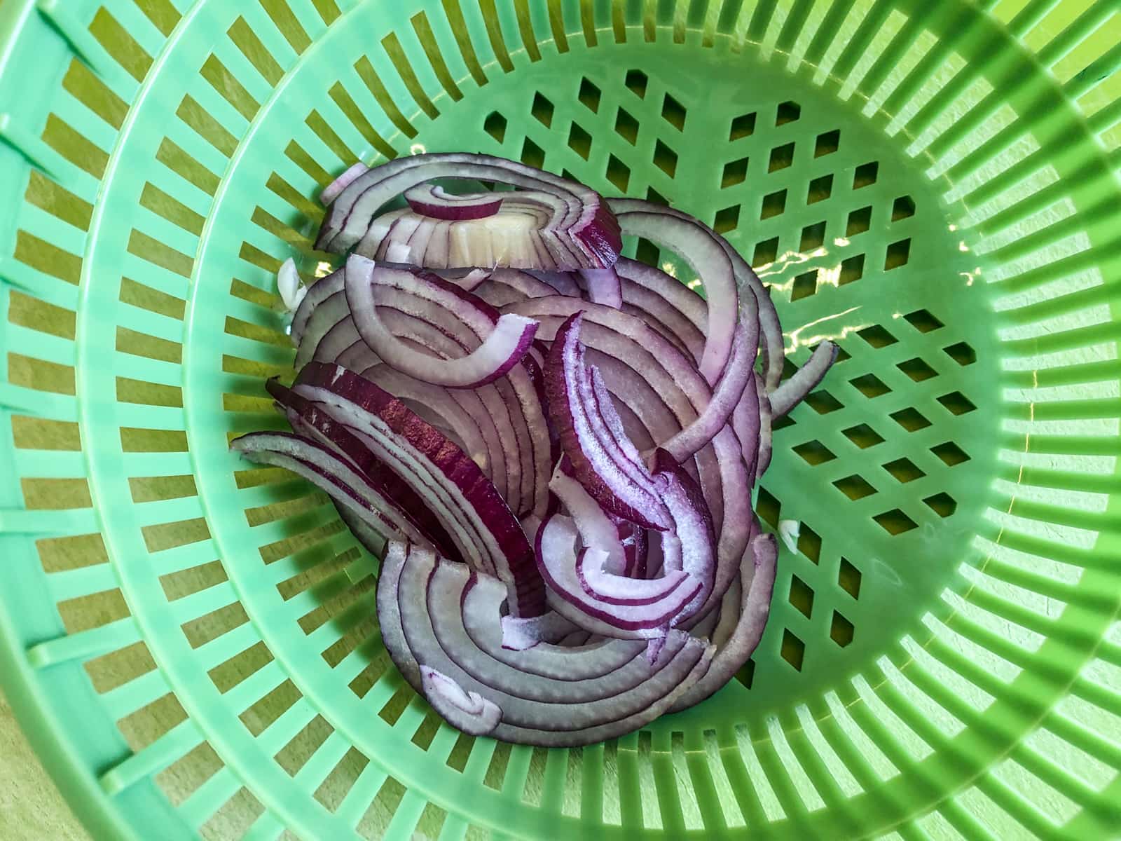 Sliced red onions in a strainer.