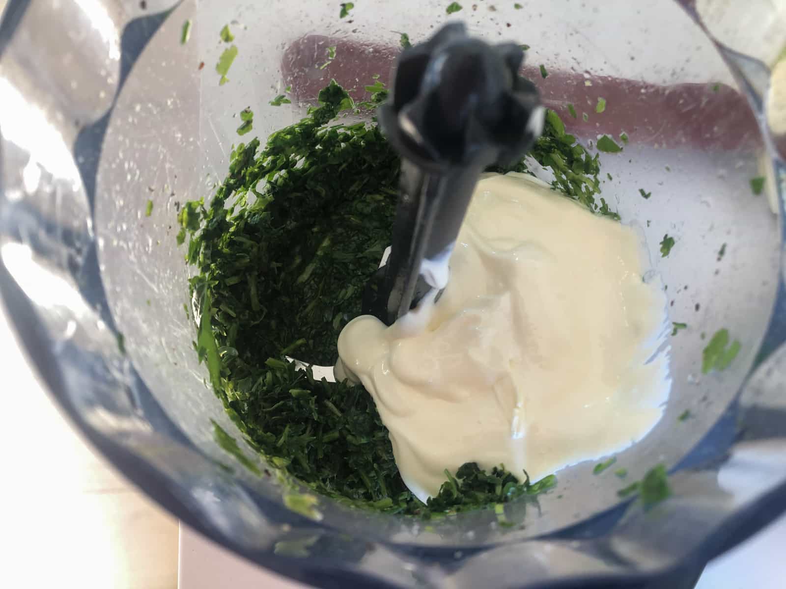 Herbs and yogurt in a small hand blender to make a dressing