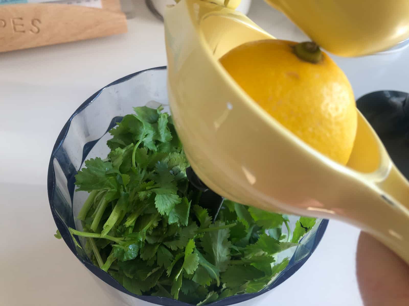 Fresh lemon juice squeezed into a small blender of fresh herbs.