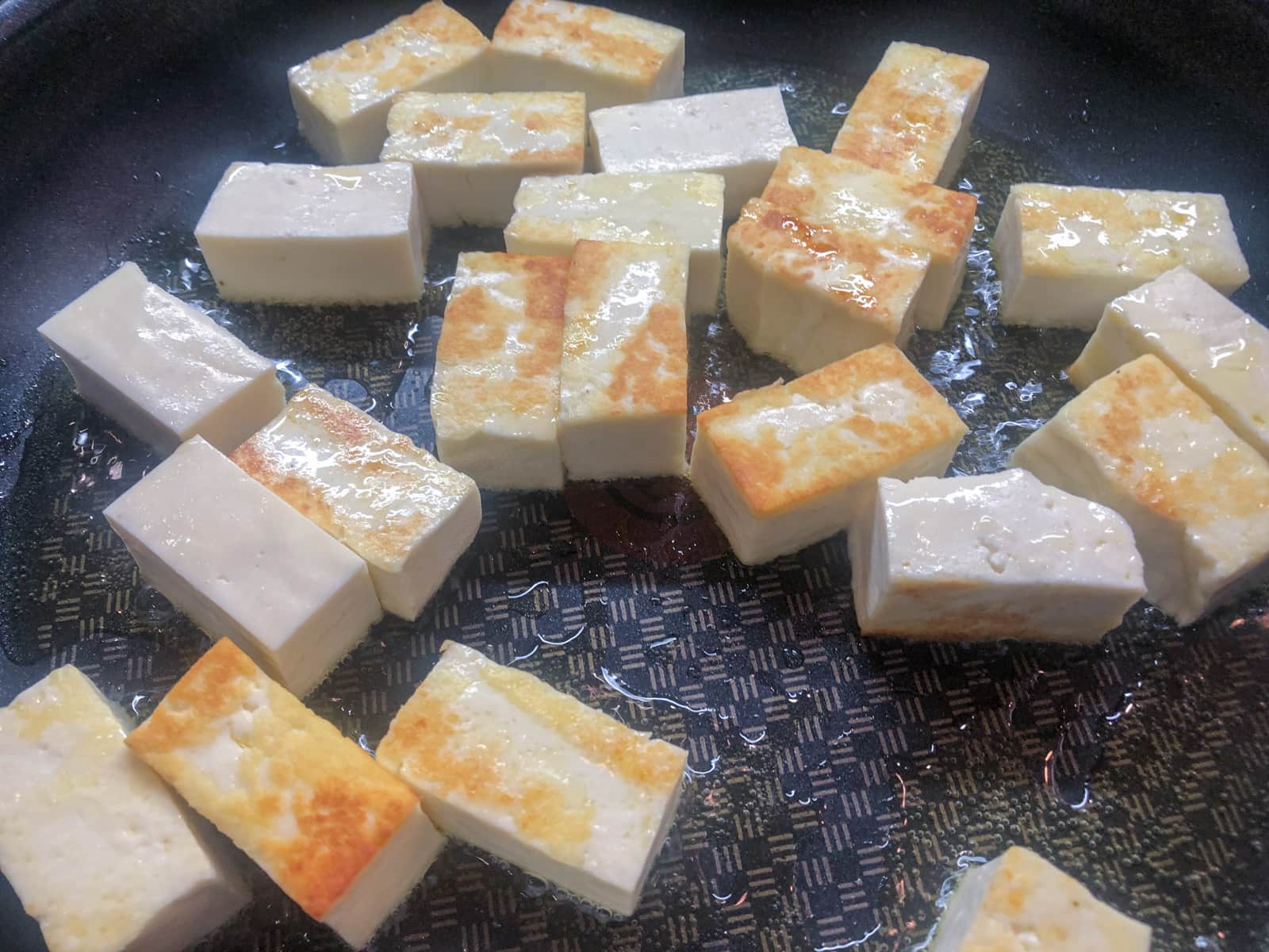 Colour starting to show on paneer cheese being fried in ghee.