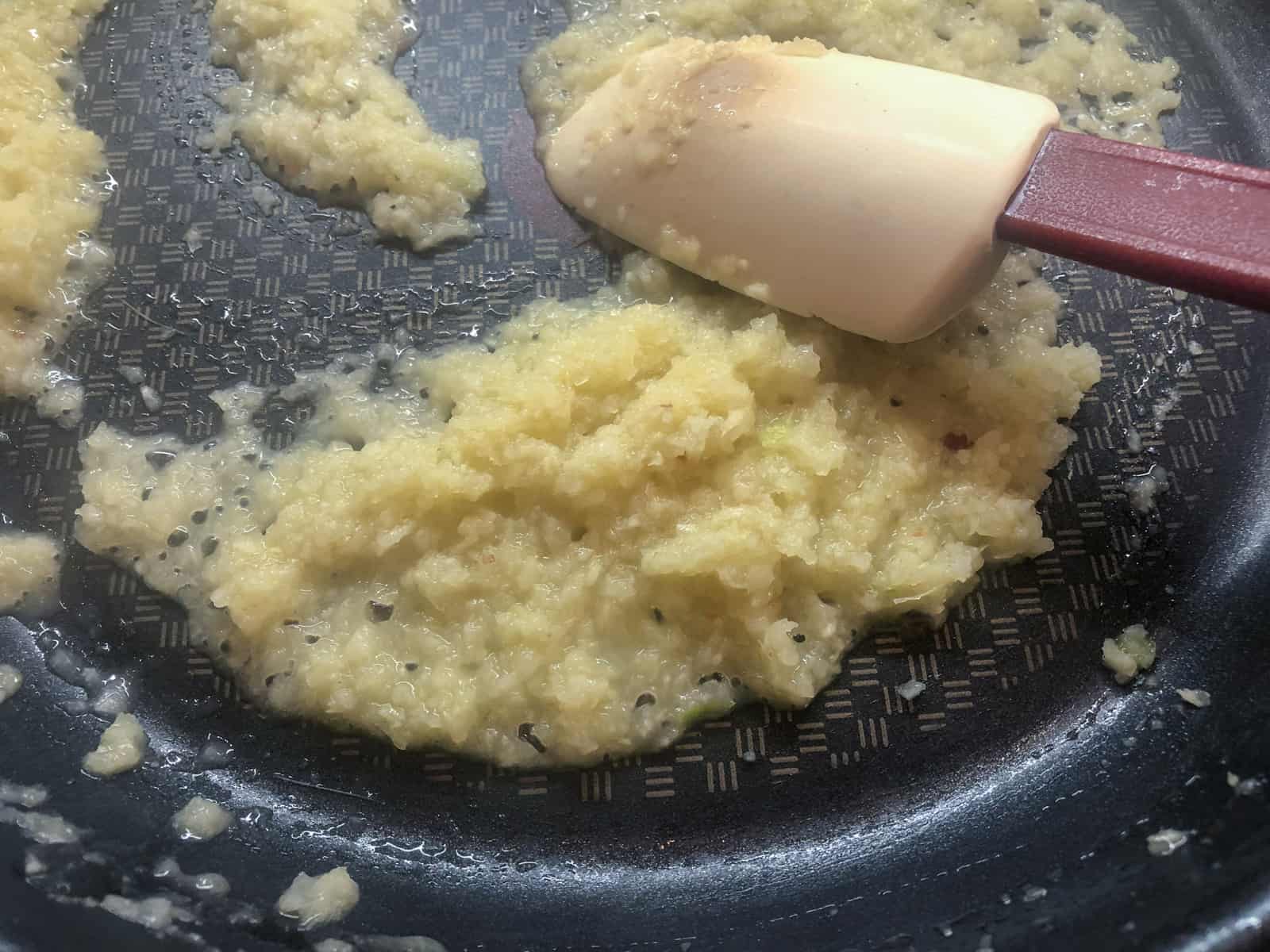An onion and garlic paste frying in a skillet in ghee.