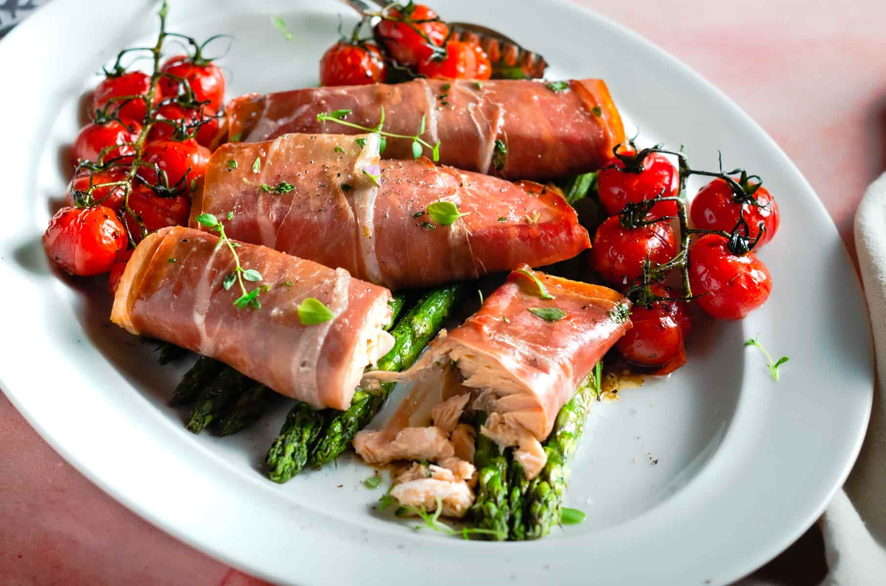A mixed platter of salmon baked in parma ham served with asparagus and oven tomatoes.