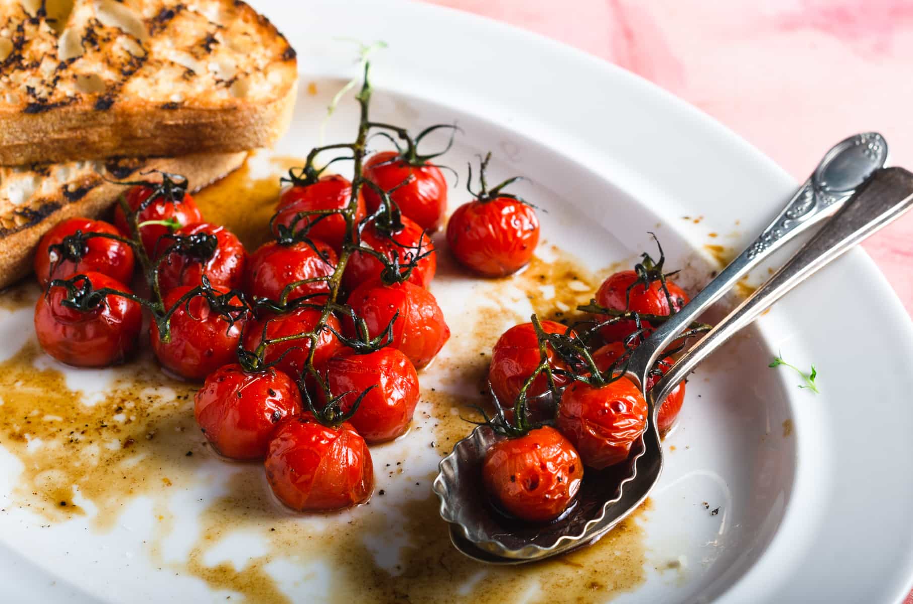 Oven roasted vine tomatoes glazed with a balsamic dressing on a white platter.