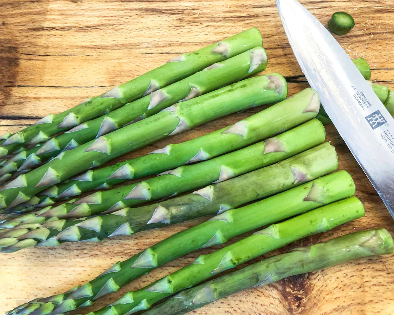 Trimming asparagus spears on a wooden board.