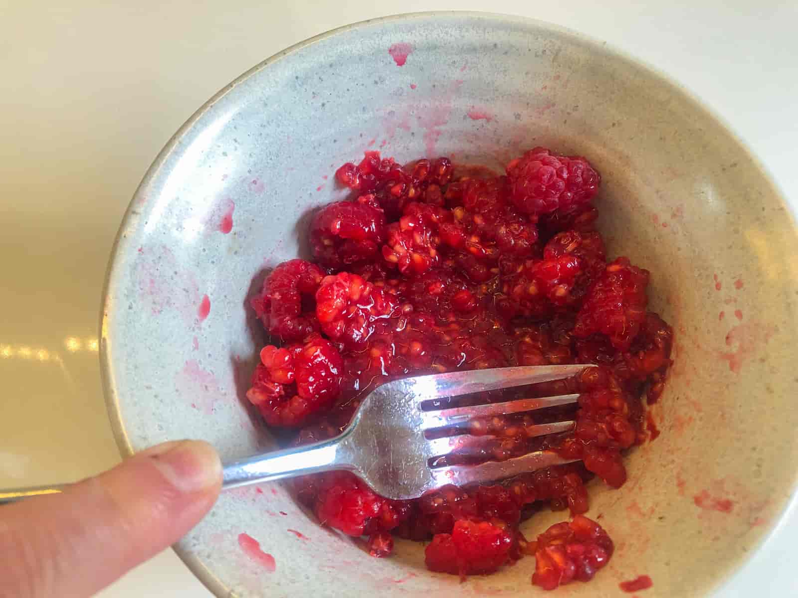 Mashing fresh Scottish raspberries with a fork.